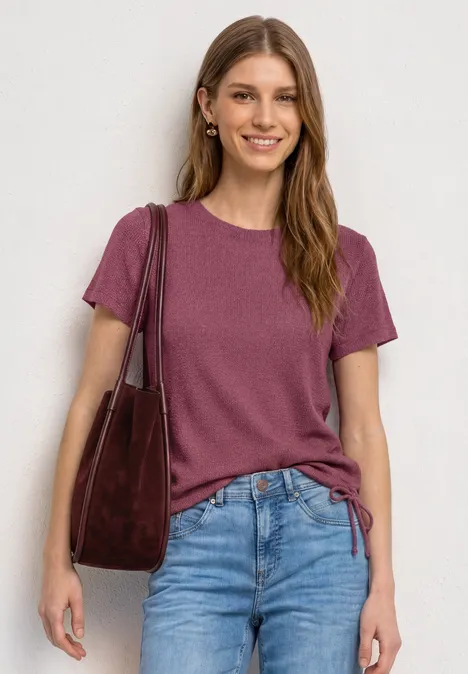 Basic T-Shirt im Strick-Look mit Rundhals dark clouded blush Frau in Jeans mit violettem T-Shirt und roter Schultertasche.