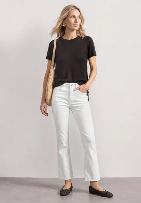 Basic T-Shirt im Strick-Look mit Rundhals black coffee Person steht lässig in schwarzem T-Shirt, weißen Jeans, schwarzen Ballerinas und trägt eine beige Tasche.