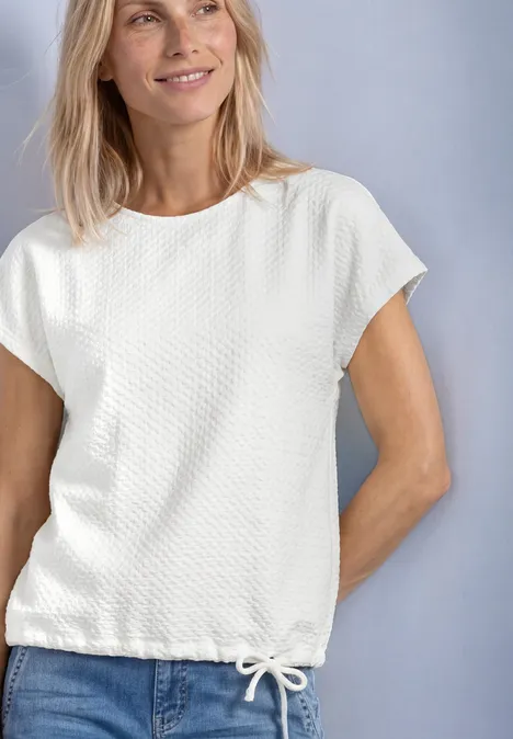 T-Shirt aus Spitze mit Rundhals off white Frau mit blondem Haar trägt weißes, strukturiertes Kurzarmshirt mit Kordelzug am Saum.