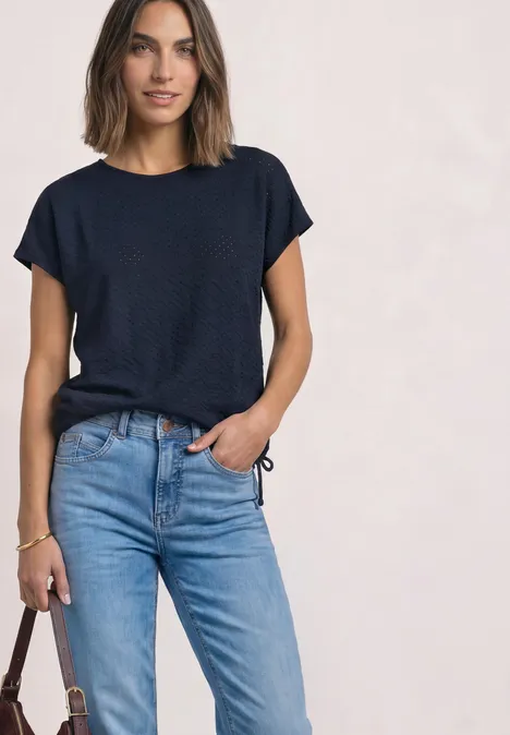 T-Shirt aus Spitze mit Rundhals darkest blue Frau in dunkelblauem T-Shirt und hellblauen Jeans, hält eine braune Tasche locker in der Hand.
