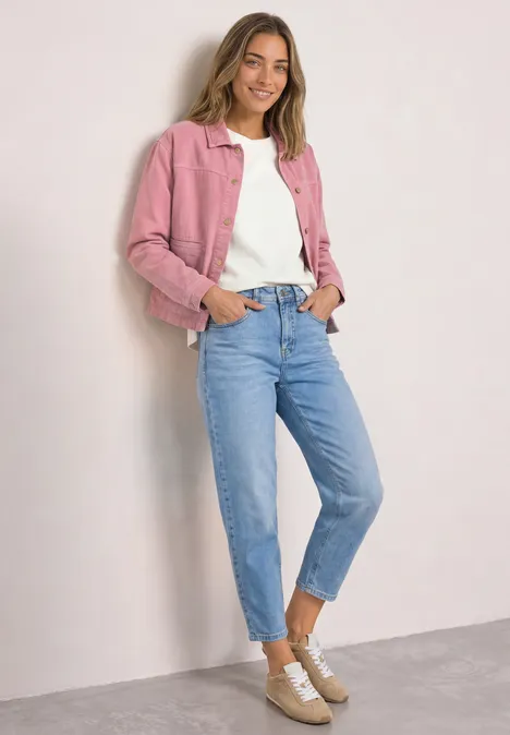 T-shirt à col rond et texturé off white Eine Frau trägt rosa Jacke, weißes Shirt, blaue Jeans und beigen Sneaker vor hellem Hintergrund.