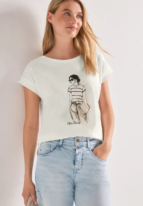 Frau trägt weißes T-Shirt mit schwarzer Linienzeichnung einer sitzenden Person und hellen Jeans