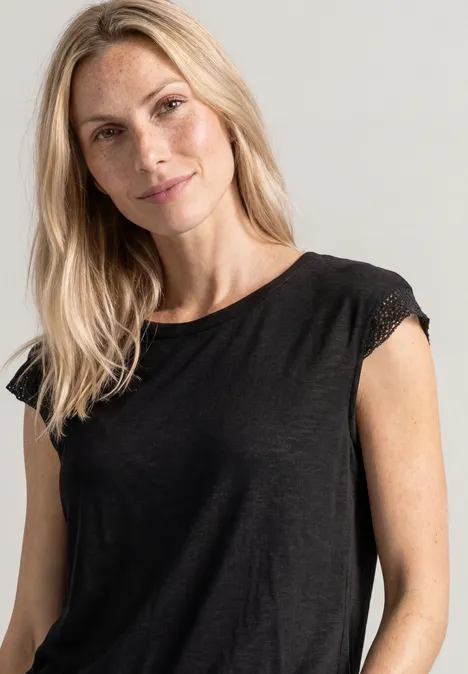 Eine lächelnde blonde Frau in einem schlichten schwarzen Oberteil, die in die Kamera blickt.
