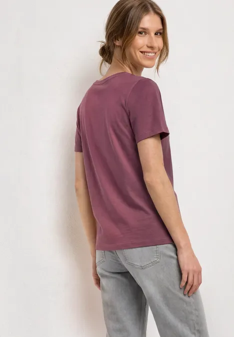 T-Shirt mit Rundhals und Frontprint dark clouded blush Frau in lila T-Shirt und grauer Jeans steht seitlich vor hellem Hintergrund