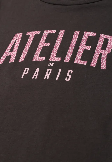 Schwarzes T-Shirt mit pinker Aufschrift 'ATELIER de PARIS'.