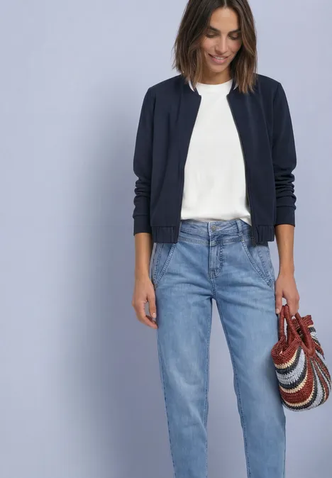 Langarm Jacke im Silk-Look mit Zipper darkest blue Frau trägt weißes T-Shirt, einen dunkelblauen Cardigan und helle Jeans, sie hält eine bunte Umhängetasche.