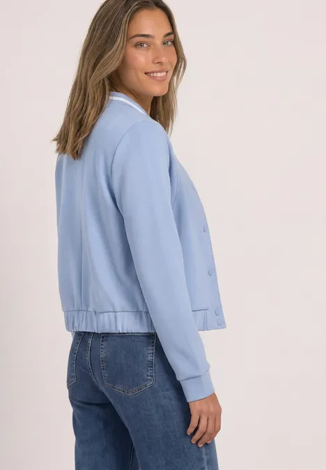 Langarm Jacke im Silk-Look mit Zipper whispery blue Junge Frau trägt hellblaue Jacke und Jeans, blickt lächelnd über die Schulter vor hellem Hintergrund.