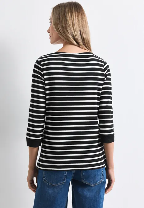 Shirt met 3/4-mouwen en een boothals Black Frau von hinten in schwarzem, weiß geringeltem 3/4-Arm-Shirt und blauen Jeans.
