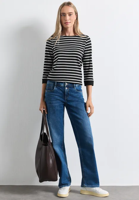 Shirt met 3/4-mouwen en een boothals Black Frau mit schwarz-weiß gestreiftem Shirt, blauen Jeans und großer Tasche.