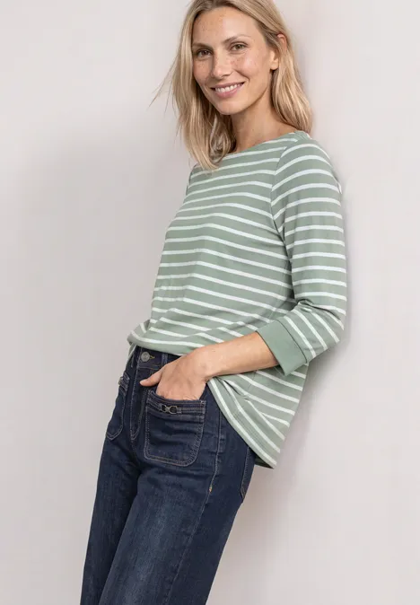 Frau mit grün-weiß gestreiftem Pullover und Jeans, lächelnd