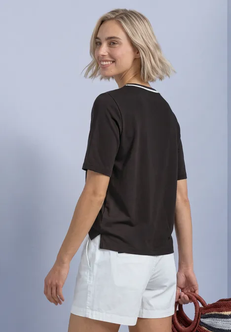 Shirt met ronde hals en contrasterende details black coffee Junge Frau mit blondem Bob, schwarzem T-Shirt und weißen Shorts, blickt über die Schulter, trägt rotes Accessoire
