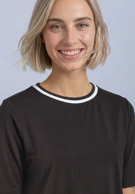 T-shirt à col rond avec détail contrasté black coffee Eine lächelnde blonde Frau in schwarzem T-Shirt vor hellem Hintergrund.