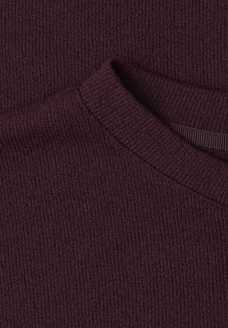 Nahaufnahme eines dunkelvioletten Strickpullovers mit Rundhalsausschnitt.