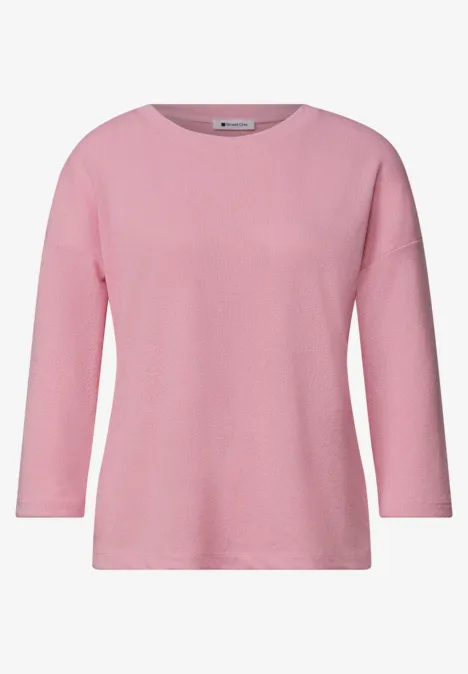 Ein schlichtes rosa Langarmshirt mit Rundhalsausschnitt.