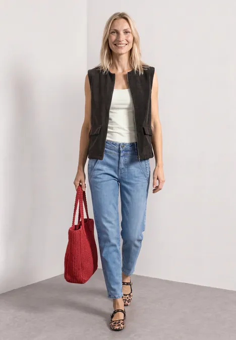 Vest met ronde hals in corduroy-look black coffee Een vrouw in jeans, wit topje en zwart vest draagt een rode tas en loopt met een glimlach.