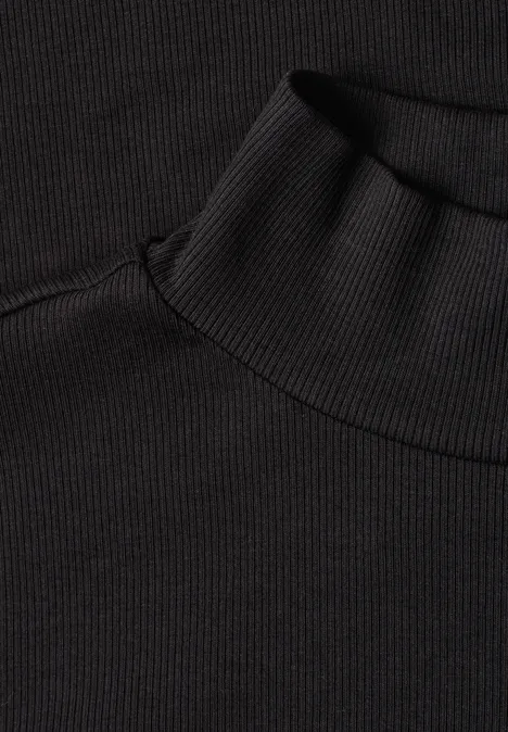 Nahaufnahme eines schwarzen Rollkragenpullovers aus geripptem Stoff.