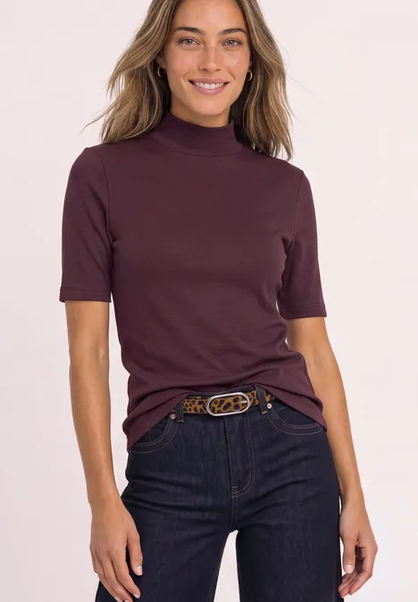 Shirt met col in geribbelde structuur rustic rouge Eine lächelnde Frau trägt ein weinrotes Kurzarm-Longsleeve mit Stehkragen und Jeans mit Gürtel.