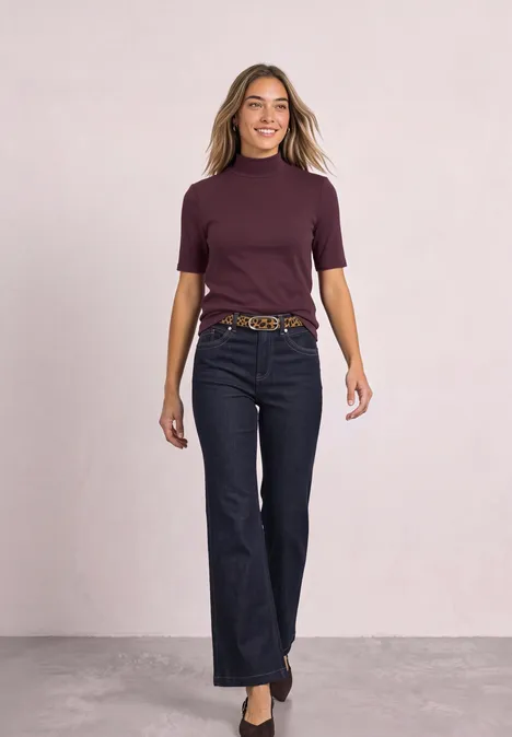 Shirt met col in geribbelde structuur rustic rouge Eine Frau im lila Kurzarmshirt und dunkler Jeans läuft selbstbewusst auf neutralem Hintergrund.