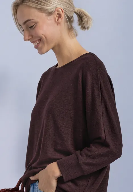 Batwing-Shirt in gemêleerde look rustic rouge mel. Vrouw met licht haar in paardenstaart draagt een bordeauxrood shirt met lange mouwen en glimlacht opzij.