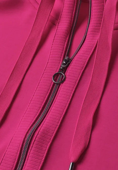 Gros plan d’un tissu rose vif avec une fermeture éclair à anneau et des plis verticaux.