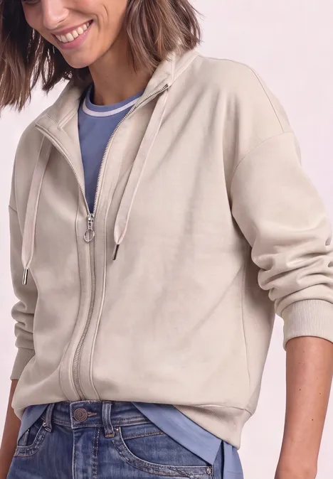 Jacke im Silk-Look mit Rippdetails clay sand Frau trägt beigen Zip-Hoodie über blauem Shirt und Jeans.
