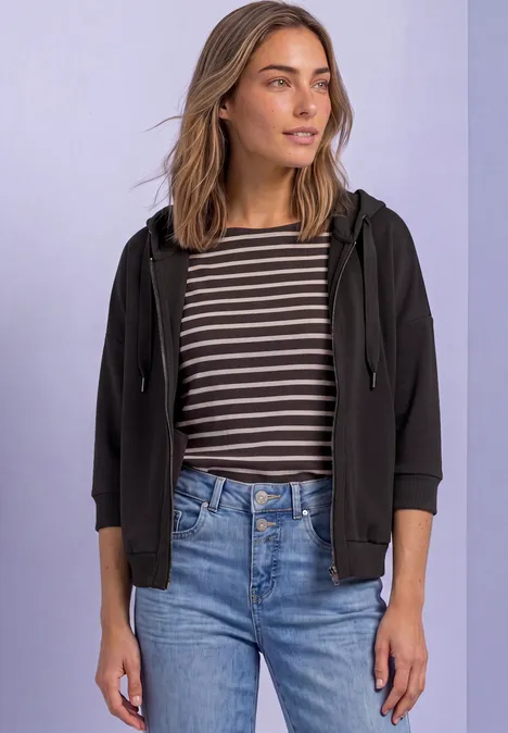 Jacke im Silk-Look mit Rippdetails black coffee Frau mit gestreiftem Shirt, schwarzer Kapuzenjacke und Jeans steht vor hellem Hintergrund.