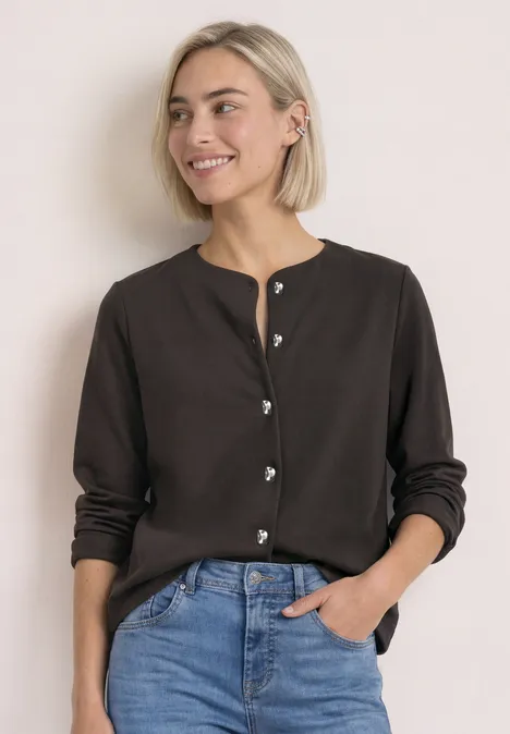 Strick-Look Jacke mit dekorativen Knöpfen black coffee Frau mit kurzen blonden Haaren lächelt, trägt braunen Cardigan und Jeans vor hellem Hintergrund.