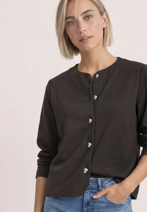 Strick-Look Jacke mit dekorativen Knöpfen black coffee Frau mit kurzem blondem Haar trägt dunkelbraune Strickjacke mit Herzknöpfen, eine Hand in Jeans-Tasche.