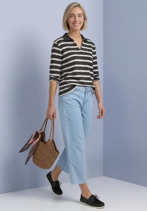 Polo met 3/4-mouwen en streepjespatroon black coffee Vrouw met gestreepte trui, lichte jeans, zwarte loafers en rotan tas