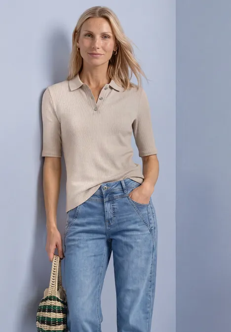 Poloshirt im Strick-Look mit Rippstruktur clay sand mel. Eine Frau trägt ein beiges Poloshirt und blaue Jeans, hält eine geflochtene Tasche in der Hand.