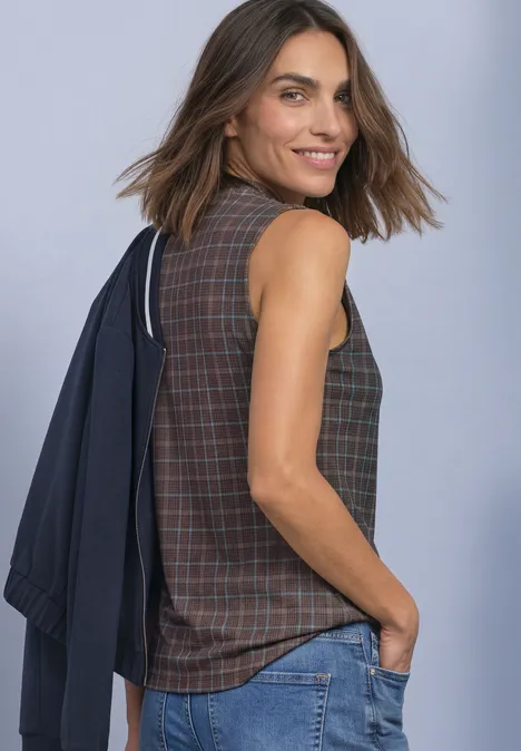 Turtleneck-top van mesh met print silk brown Vrouw glimlacht opzij, draagt blazer over schouder, ruitjes top en spijkerbroek.