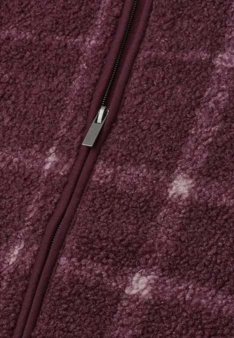 Blick auf einen geschlossenen Reißverschluss an weichem, burgunderfarbenem Fleece mit dezentem Karomuster.