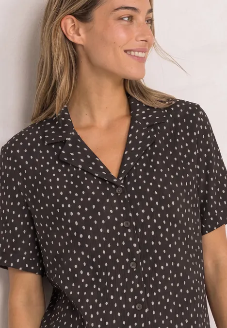 Shirt met verschillende texturen en een knoopsluiting black coffee Een glimlachende vrouw draagt een zwart kort mouwen overhemd met een subtiel wit patroon.