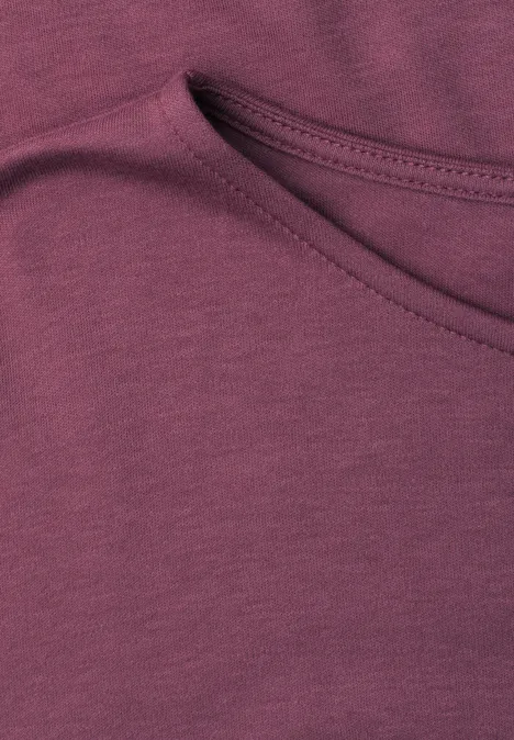Nahaufnahme eines beerenfarbenen Baumwollshirts mit einem schräg angesetzten Einschubtaschendetail.