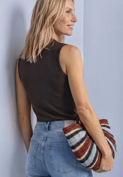 Top in Silk-Look met coltrui black coffee Frau von der Seite in Jeans und schwarzem Top, hält bunte gestreifte Tasche.