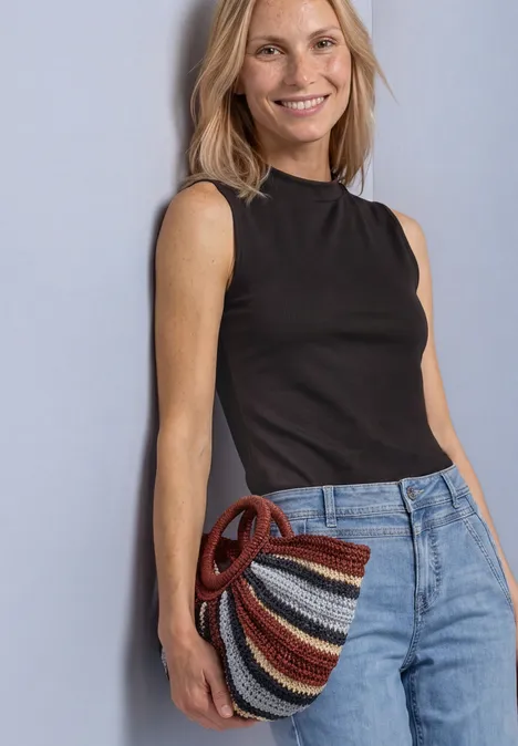Top in Silk-Look met coltrui black coffee Lächelnde Frau in schwarzem Top und Jeans hält eine bunte, gestreifte Flechttasche.