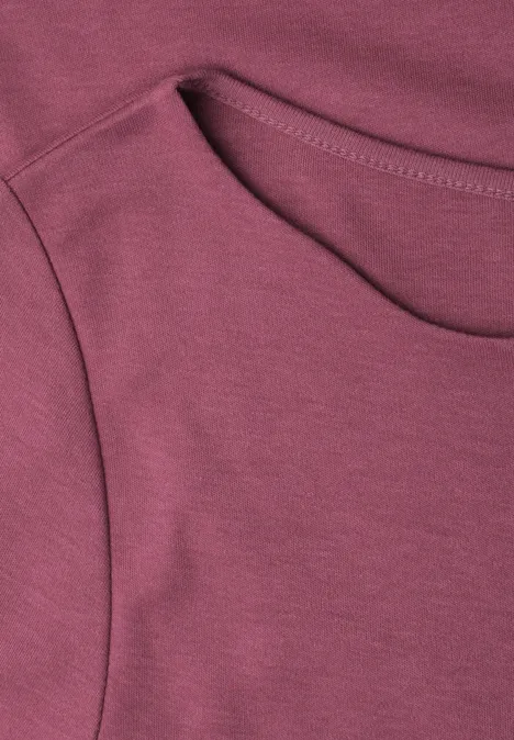 Nahaufnahme eines bordeauxfarbenen T-Shirts mit Rundhalsausschnitt und sichtbarer Naht.