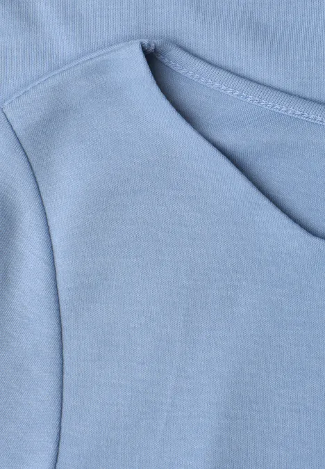 Nahaufnahme einer hellblauen Kapuzenpullover-Tasche mit sichtbaren Nähten.