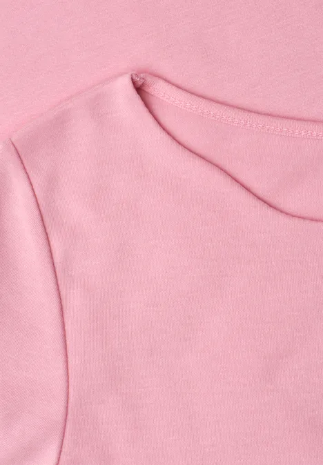 Gros plan d’un T-shirt rose avec encolure ronde et coutures apparentes.