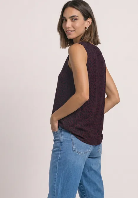 Top mit V-Neck und Dekodetail rustic rouge Frau im dunkelroten Ringeltop und blauen Jeans, seitlich stehend mit Händen in den Taschen, schaut über die Schulter.