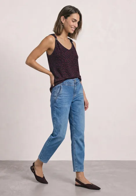 Top mit V-Neck und Dekodetail rustic rouge Eine junge Frau lächelt in schwarzem Top, blauen High-Waist-Jeans und schwarzen Ballerinas.