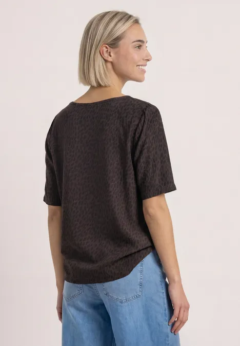T-Shirt mit Rundhals und Strukturmix molten earth Frau von hinten mit kurzem, gemustertem T-Shirt in Dunkelbraun und hellblauen Jeans.