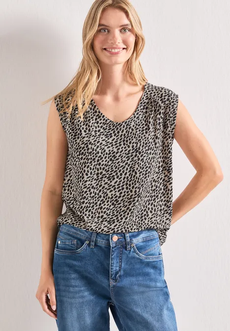 Shirt mit Boat Neck und Elastikbund cotton beige Frau trägt ärmelloses Leoprint-Top und blaue Jeans vor neutralem Hintergrund.