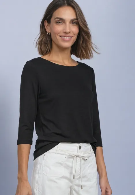 Shirt met 3/4-mouwen en een boothals Black Eine Frau trägt ein schwarzes 3/4-Ärmel-Shirt und helle, locker sitzende Hose mit Bindegürtel.
