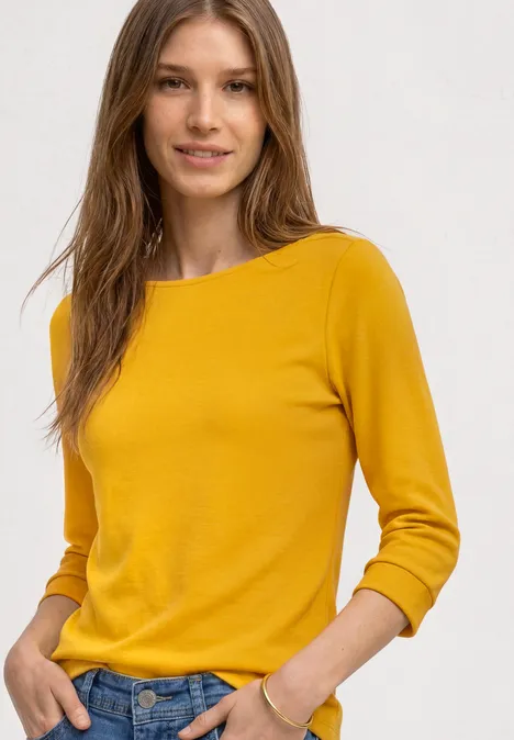 Frau in gelbem Pullover und Jeans.