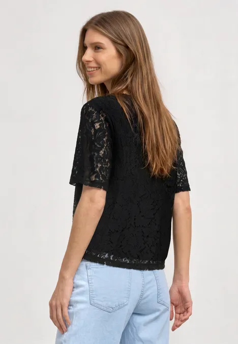 Frau von hinten in schwarzer Spitzenbluse mit kurzen Ärmeln und blauer Jeans.