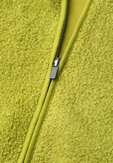Close-up van een lichtgroene ritssluiting op zacht fleece.