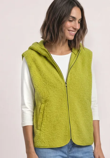 Damesvest van groen fleece met capuchon, ritssluiting en zakken, gedragen over een wit shirt.