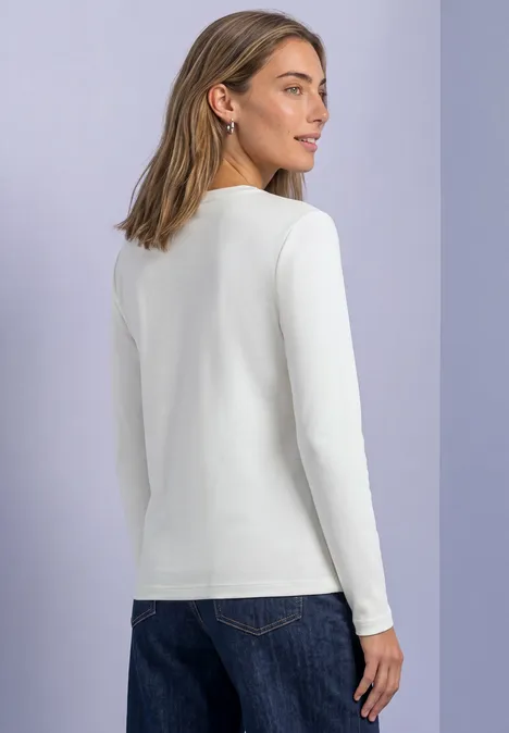 Bluzka Basic z dekoltem w łódkę off white Kobieta w białej bluzce z długim rękawem i dżinsach, widok od tyłu, pastelowe tło.