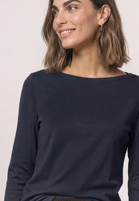 Porträt einer lächelnden Frau in dunkelblauem Langarmshirt, halbfigur, Blick nach rechts.
